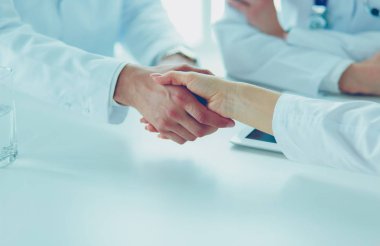 Doktorlar el ele tutuşup yakın çekim yapıyor.