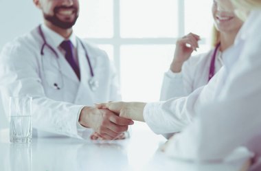 Doktor ofiste erkek bir hastayla el sıkışıyor.