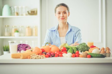 Ahşap iç kısımda meyve ve sebze dolu masada oturan genç ve tatlı bir kadın..