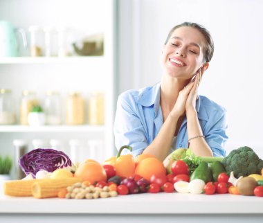 Ahşap iç kısımda meyve ve sebze dolu masada oturan genç ve tatlı bir kadın..