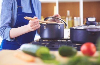 Mutfakta ahşap kaşıkla yemek pişiren kadın