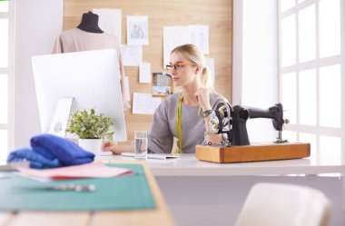 Masasında dikiş makinesi olan bir fabrikada genç ve güzel bir kız.