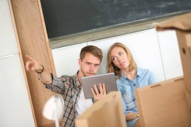 Genç bir çift yeni ev içinde hareket. Oturma ve açma sonra rahatlatıcı. Bir şey üstünde laptop arıyorum. Genç Çift