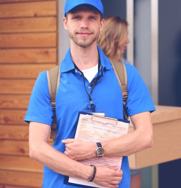 Mavi üniformalı gülümseyen kurye servis konseptine paket kutusu teslim eden teslimatçı. Mavi üniformalı gülümseyen teslimatçı.