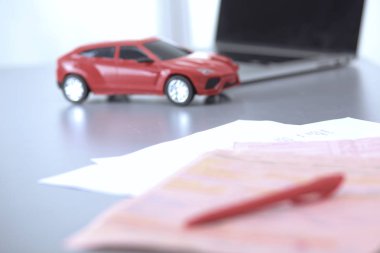 Bilgisayarın yanında kalem ve kırmızı bir oyuncak araba olan bir dizüstü bilgisayar. Nesne çekimi