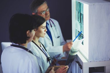 Bir grup doktor bir klinikte röntgenleri inceliyor, teşhis koymayı düşünüyorlar.