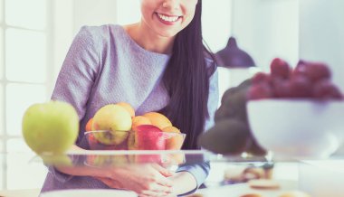 Gülümseyen kadın buzdolabından taze meyve alıyor, sağlıklı yiyecek konsepti.