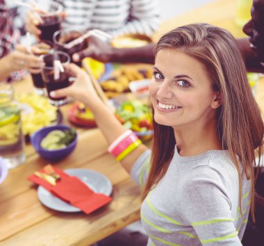 Ahşap masada otururken birlikte yemek yiyen bir grup insanın üst düzey görüntüsü. Masada yemek var. İnsanlar fast food yiyor. Bir kızın portresi.
