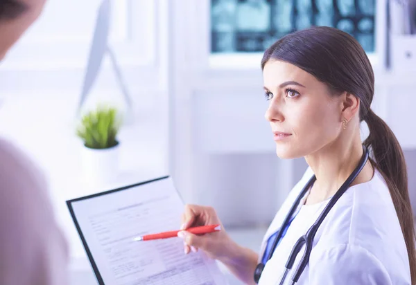 Hermosa doctora explicando el tratamiento médico a un paciente — Foto de Stock