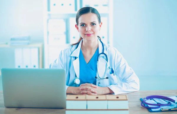 Beautiful young smiling female doctor sitting at the desk and writing. female doctor — Stock Photo, Image