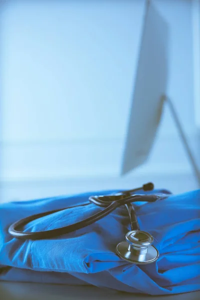 诊疗室桌上的听诊器和医生外套的图像。医疗概念 — 图库照片