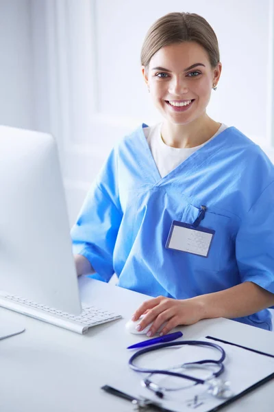 Young tired exhausted woman sitting at desk, working on computer with medical documents