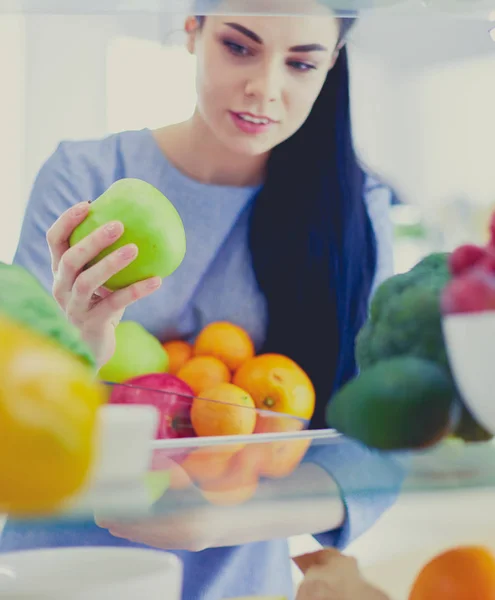 Smiling woman taking a fresh fruit out of the fridge, healthy food concept — Stock Photo, Image