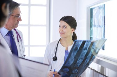 Hastanedeki röntgenlere bakarak hastaların teşhisini tartışan gülümseyen doktorlar