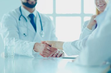 Doktor ofiste erkek bir hastayla el sıkışıyor.