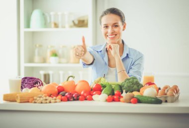 Ahşap iç kısımda meyve ve sebze dolu masada oturan genç ve tatlı bir kadın..