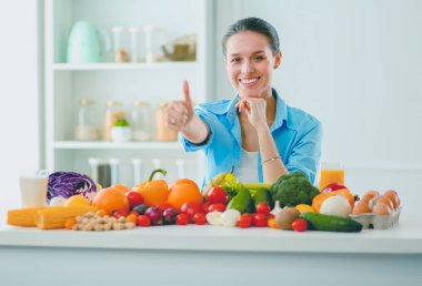 Ahşap iç kısımda meyve ve sebze dolu masada oturan genç ve tatlı bir kadın..