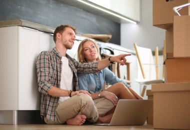 Genç bir çift yeni ev içinde hareket. Oturma ve açma sonra rahatlatıcı. Bir şey üstünde laptop arıyorum. Genç Çift