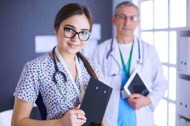 Bir doktor ekibi, kadın ve erkek, ofiste bekliyorlar.