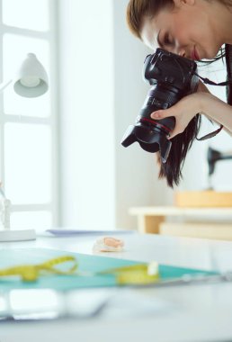İşyerinin yanında duran ve dijital fotoğraf makinesinde fotoğraflayan genç kadın tasarımcı