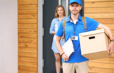 Mavi üniformalı gülümseyen kurye servis konseptine paket kutusu teslim eden teslimatçı. Mavi üniformalı gülümseyen teslimatçı.