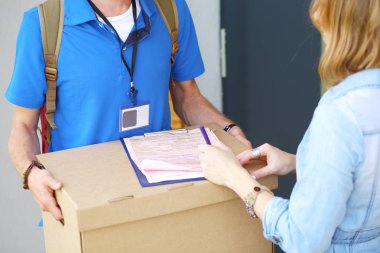 Mavi üniformalı gülümseyen kurye servis konseptine paket kutusu teslim eden teslimatçı. Mavi üniformalı gülümseyen teslimatçı.
