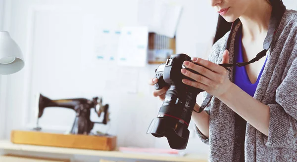 Giovane donna designer in piedi vicino al posto di lavoro e fotografarlo sulla macchina fotografica digitale — Foto Stock