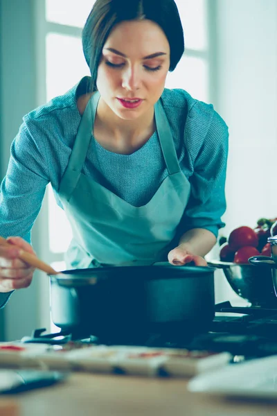 Frau steht am Herd in der Küche, kocht und riecht die schönen Düfte . — Stockfoto