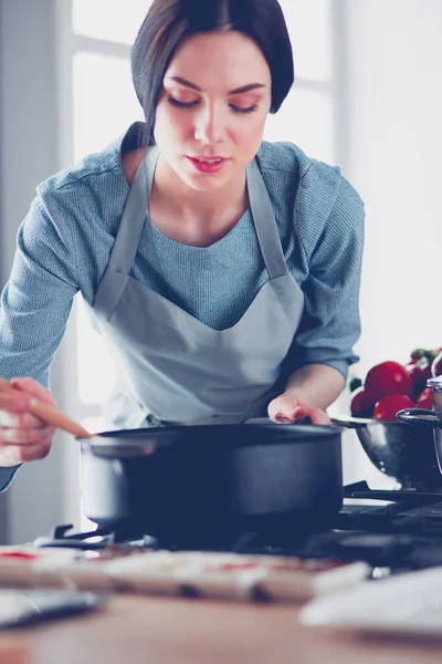 Frau steht am Herd in der Küche, kocht und riecht die schönen Düfte . — Stockfoto