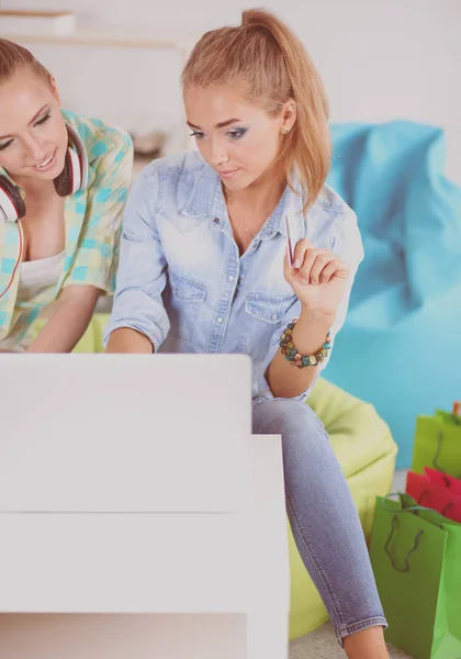 Zwei junge Schwestern sitzen auf dem Sofa, im Wohnzimmer, zu Hause, kaufen online auf einem digitalen Tablet ein, halten eine Kreditkarte in der Hand — Stockfoto