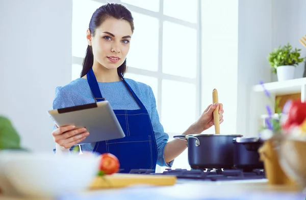 Jonge vrouw met behulp van een tablet computer om te koken in haar keuken — Stockfoto