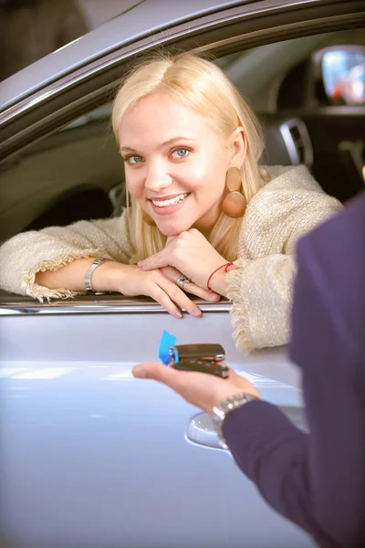 Araba satıcısı araba galerisindeki mutlu müşteriye araba satar ve anahtarları teslim eder.. — Stok fotoğraf