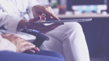 Lovely genç İspanyol kadın kıdemli doktor ile tablet bilgisayarda test sonuçlarına bakıyor.