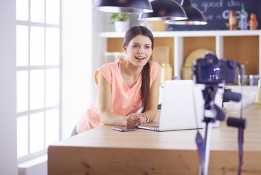 Mutfakta dizüstü bilgisayara benzeyen tariflerle gülümseyen genç bir kadın. Gıda blogcusu kavramı