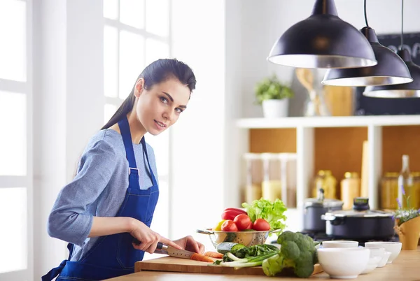 Mutfakta sebze doğrayan genç bir kadın.