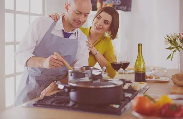 Attractive couple in love cooking and opens the wine in the kitchen while they cook dinner for a romantic evening — Stock Photo, Image