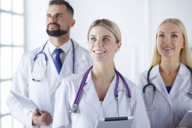 Gülümseyen doktorlar çalışırken bir arada duruyorlar.