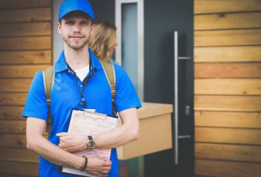 Mavi üniformalı gülümseyen kurye servis konseptine paket kutusu teslim eden teslimatçı. Mavi üniformalı gülümseyen teslimatçı.