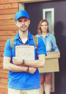 Mavi üniformalı gülümseyen kurye servis konseptine paket kutusu teslim eden teslimatçı. Mavi üniformalı gülümseyen teslimatçı.