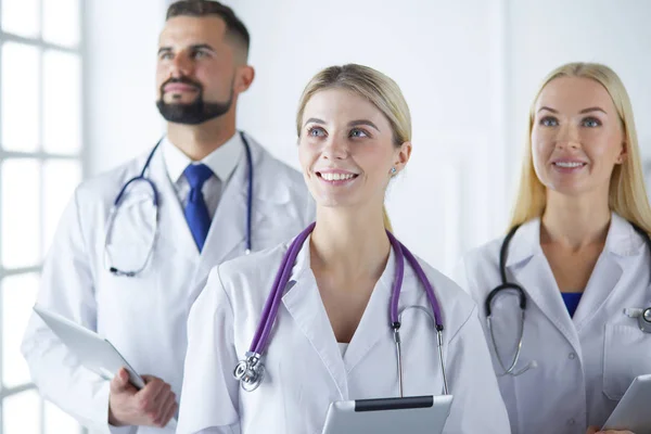 Glimlachende dokters staan allemaal samen terwijl ze werken. — Stockfoto