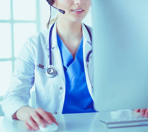 Young practitioner doctor working at the clinic reception desk, she is answering phone calls and scheduling appointments — Stock Photo, Image