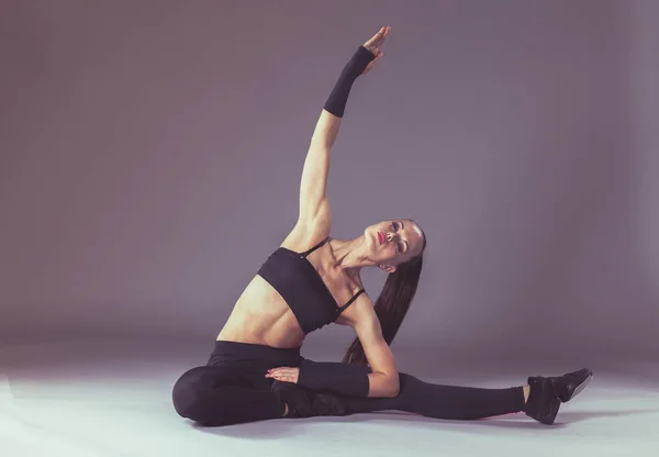 Mujer joven musculosa de pie sobre fondo gris. Una joven musculosa. hermosa chica haciendo ejercicios deportivos —  Fotos de Stock