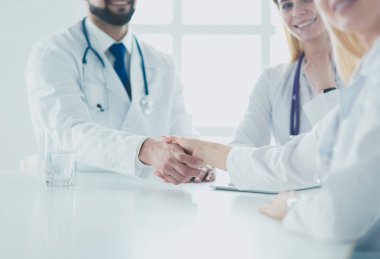 Doktor ofiste erkek bir hastayla el sıkışıyor.