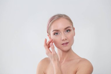 güzel genç kız temiz bir cilt bir el ile bir yanak dokunur.