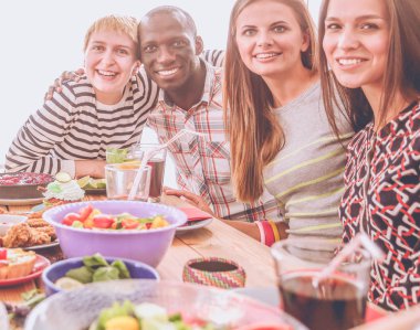 Ahşap masada otururken birlikte yemek yiyen bir grup insanın üst düzey görüntüsü. Masada yemek var. İnsanlar fast food yiyor..