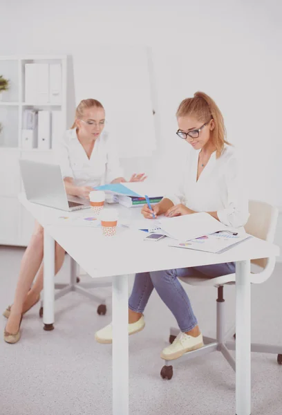 Two women working together at office, sitting on the desk — Stock Photo, Image