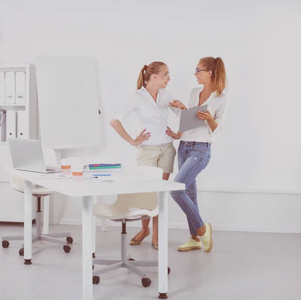 Two women working together at office, sitting on the desk — Stock Photo, Image