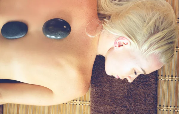 Young woman in spa salon, getting stones massage — Stock Photo, Image