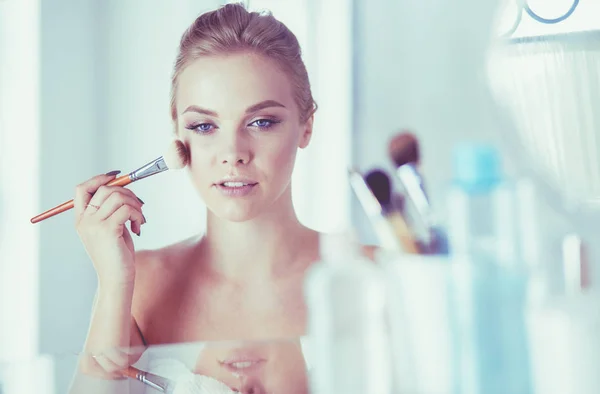 Uma foto de uma jovem mulher aplicando pó facial no banheiro — Fotografia de Stock