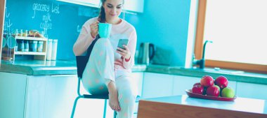 modern mutfakta otururken cep telefonu kullanan kadın